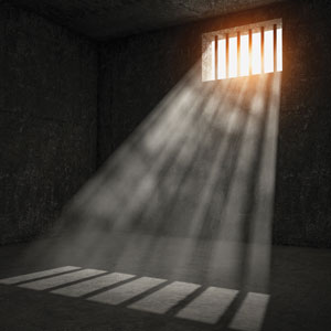 A photograph of an empty prison cell with light shining through a window.