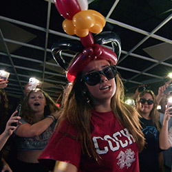 Girl with sunglasses on and a cocky-shaped balloon hat.