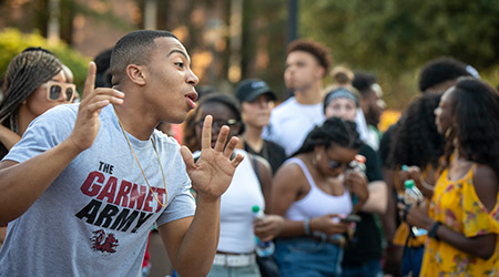 Man dancing outside in a crowd wearing a USC shirt.