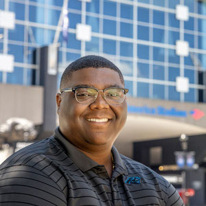 Alex Grant smiles in front of Bank of America Stadium on a sunny day