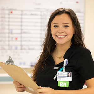 Makenzie Edwards, a recent USC Union cohort graduate, smiles at work while holding a clipboard.