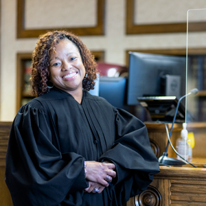 DeAndrea Benjamin wears a judge's black robe and stands in a courtroom.