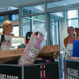 Two freshmen pushing carts with their belongings into their new campus home.