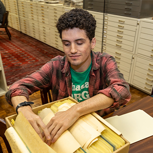 Stevie Malenowski combs through a box of papers and images in Thomas Cooper Library.