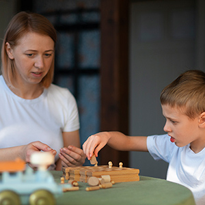 Mother plays tabletop game with young son.