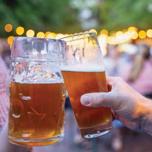Two beer glasses clink together in a toast to Bierkeller, alumni Scott Burgess’ local brewery