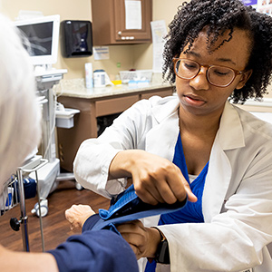 A pharmacist places a cuff on the arm of a patient to check blood pressure.