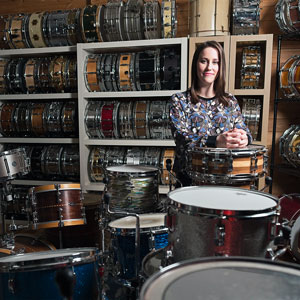 woman stands in a room filled with drums