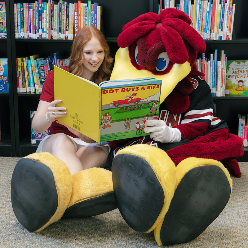 Emma Connelly and Cocky reading a children's book.