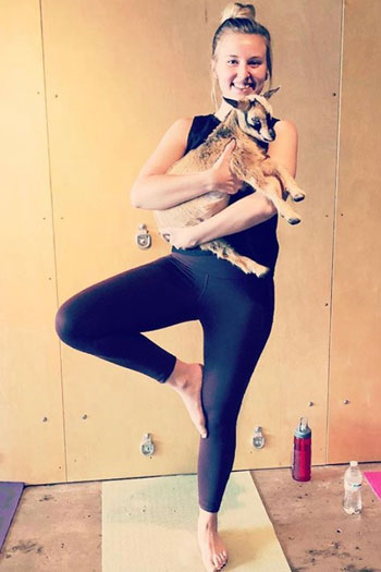 sarah sharpe in a yoga pose holding a goat