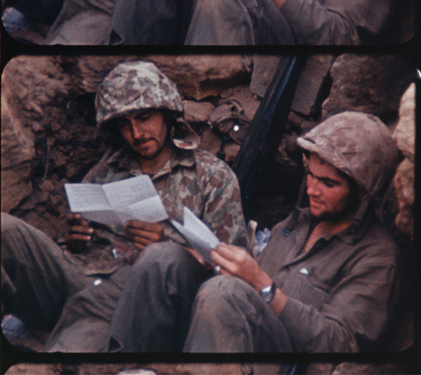 Soldiers reading letters in a foxhole at the Battle of Iwo Jima.