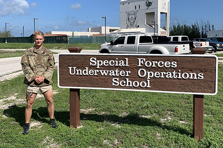 ROTC cadet standing next to Special Forces Operations Training School sign