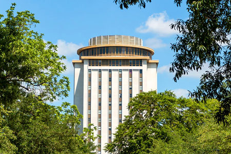 A photo of the top half of the Capstone building. The rectangular building is 18 stories high and is topped with a circular rotating restaurant.