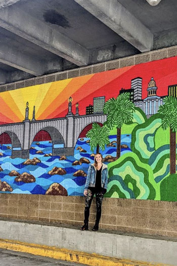 Christine Lufty standing in front of her mural