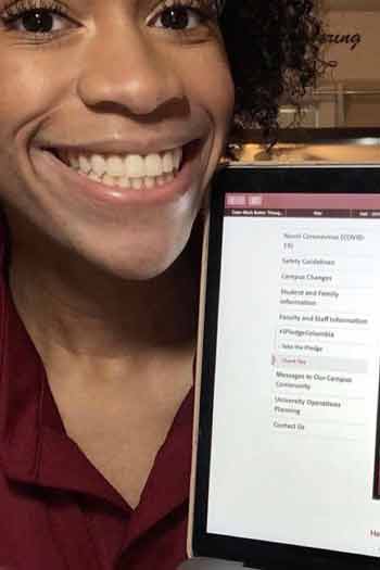 Selfie of sophomore orientation leader, jenny onyechi. She is holding up her laptop to show that she pledged to columbia
