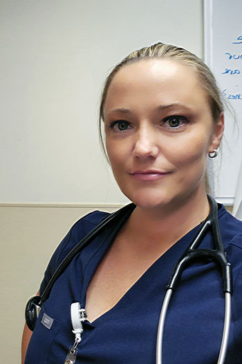 Stephanie munoz in medical scrubs stands in front of a bare wall