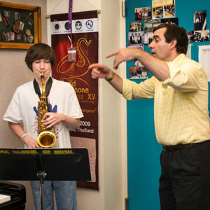 student playing saxophone with instructor directing
