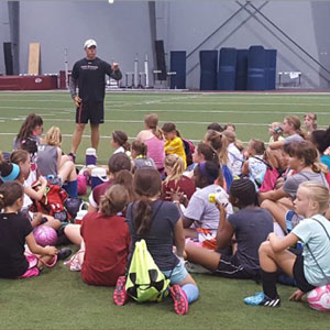 students listening to coach as soccer camp