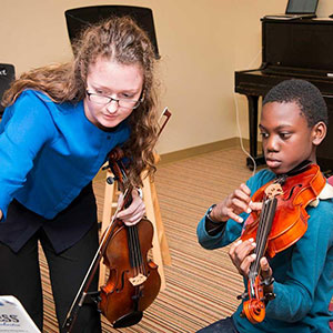 teacher and student with music stand and violins