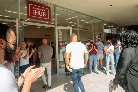 customers enter Gamecock iHub store at grand opening with employees clapping outside