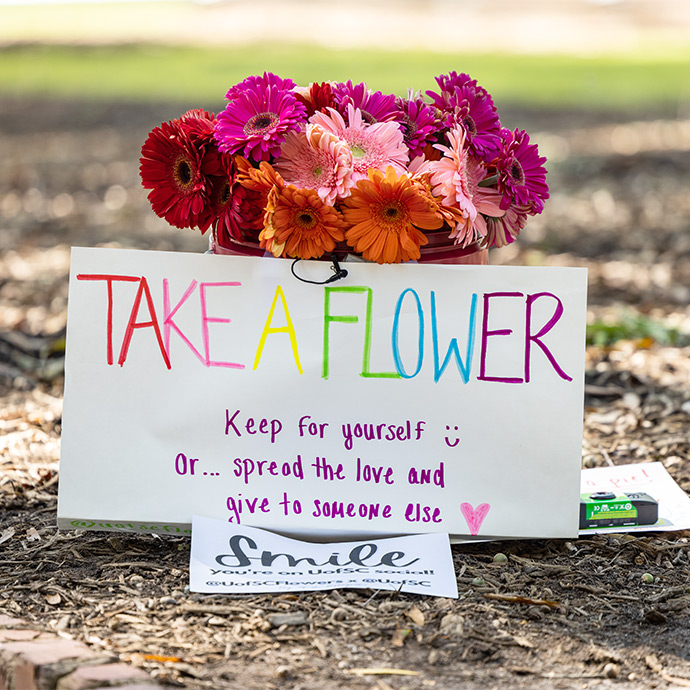 A bucket of flowers sitting on the horseshoe with a sign that reads Take a Flower. 