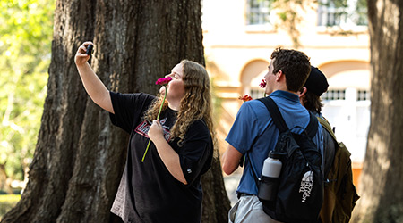 Three students taking a selfie with their flowers.