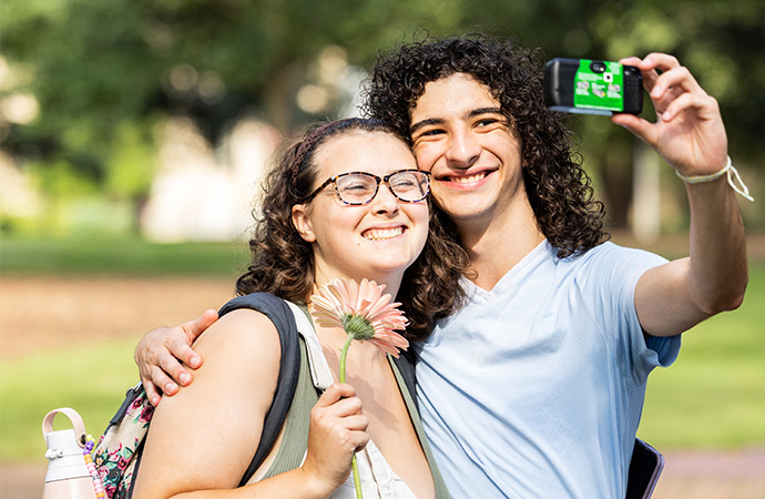 Two students taking a selfie with their flower.