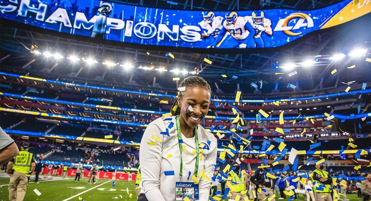 Alexa Hill ยืนอยู่บนสนามฟุตบอล NFL Los Angeles Rams โดยมีลูกปาโปรยลงมาใส่เธอ 