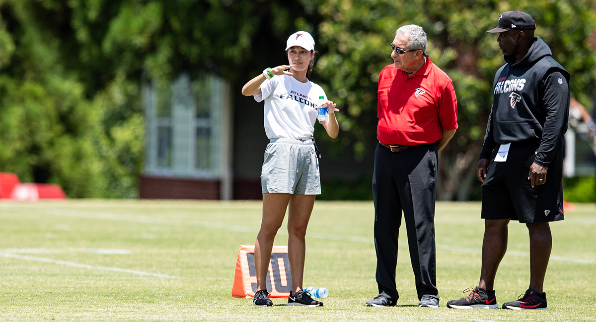 Kjahna O on the field with Atlanta Falcons player and coach. 