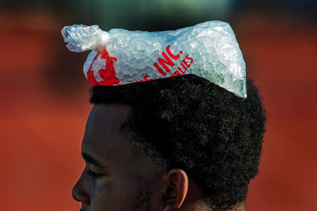 Football player with bag of ice on his head at practice