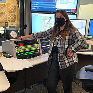 woman in a flannel posing in front of radio equipment