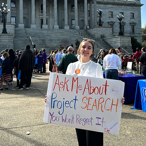 a woman in a white shirt holding a poster