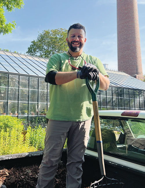 Photo of groundskeeper Omar Perez smiling for the camera with a shovel in his hand.