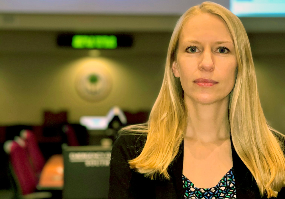 melissa potter stands with arms crossed in front of a large conference table