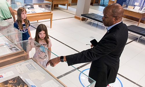 Bobby Donaldson pointing to a piece in an exhibit, showing two children.