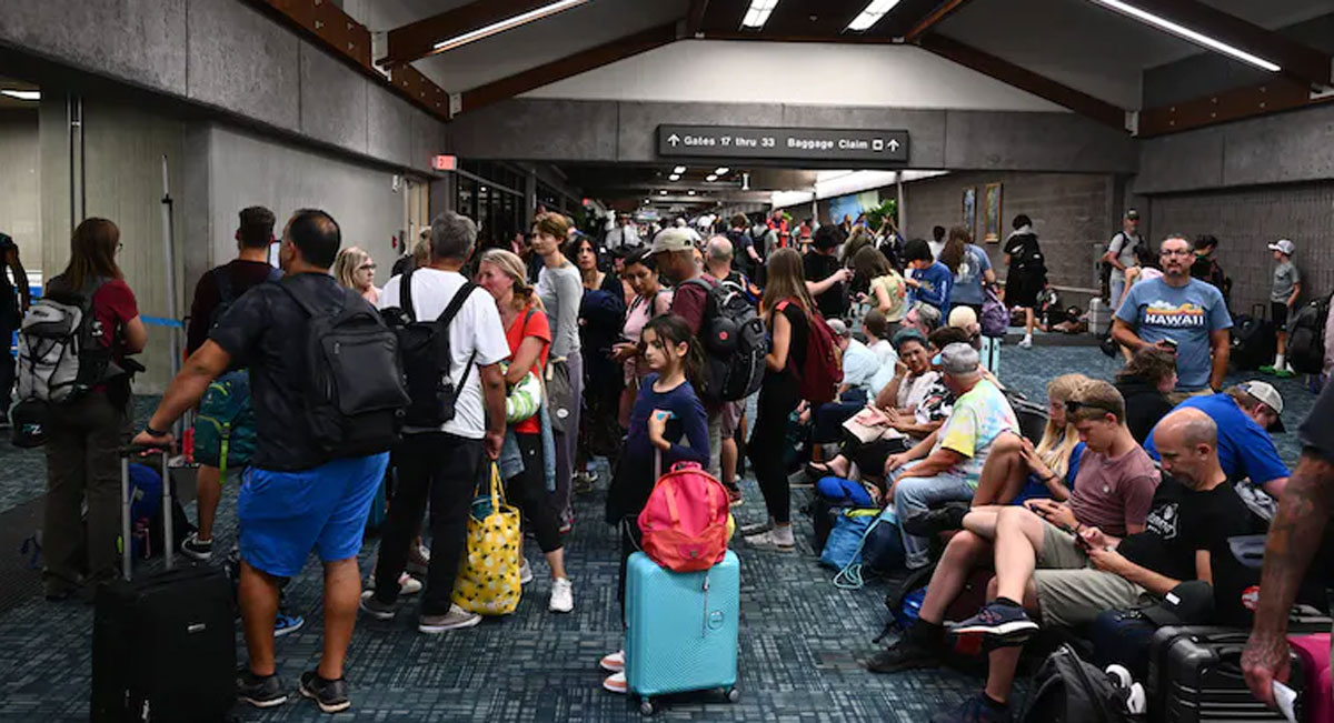 People standing, sitting and lying down around an airport departure gate.
