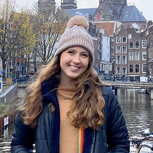 Charlotte Pollack smiles as she stands on a bridge over a river in Amsterdam