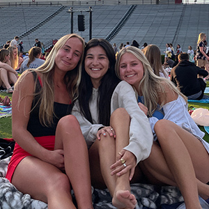 Lydia Stoehr and two friends sitting on the field at Williams-Brice stadium