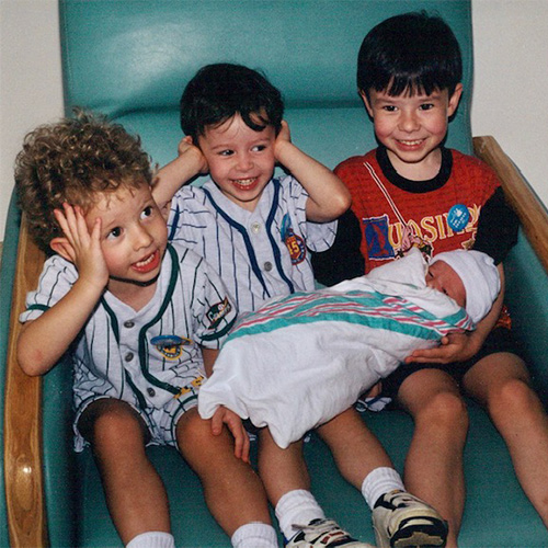 Three young boys holding an infant
