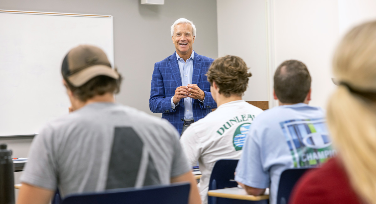 Danny Morrison stands in front of class with three students