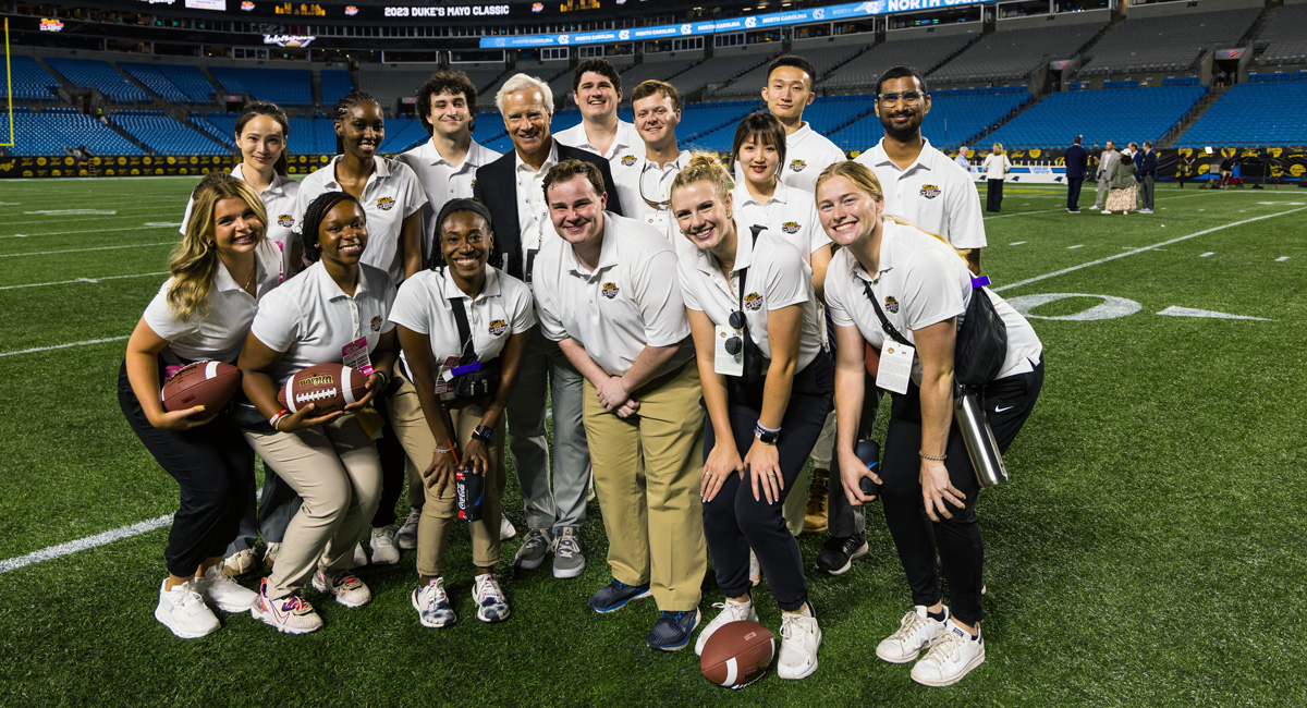 Danny Morrison and students in his class pose on the field after the USC-UNC football game at the Panthers stadium