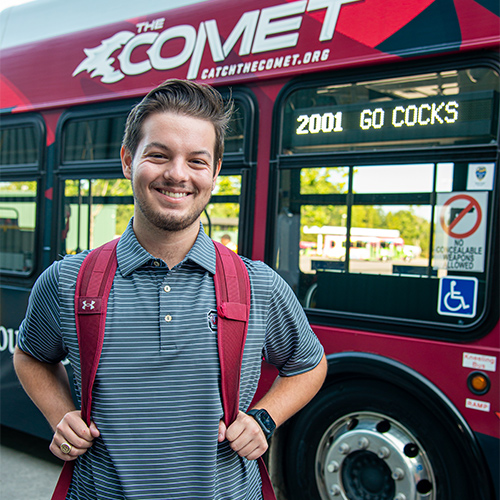 Blake Gibbons standing in front of a Comet bus in Columbia.