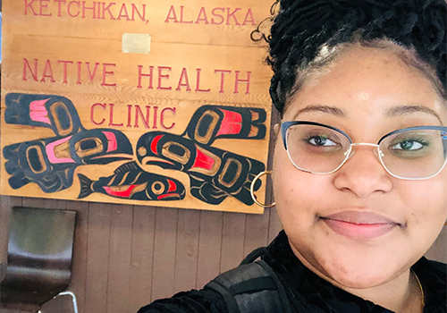Photo of Chloe Watts standing outside a health clinic in Alaska.