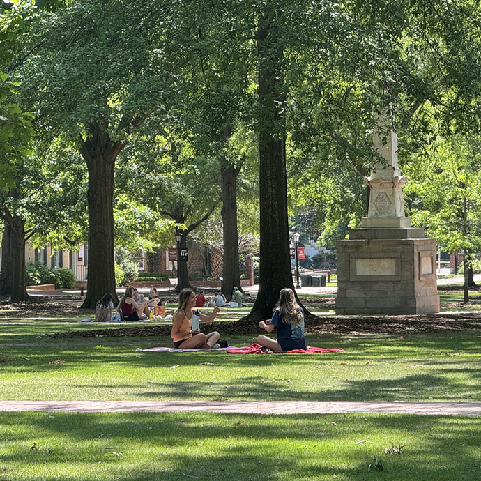 Two women on a blanket in front of Maxcy Monument