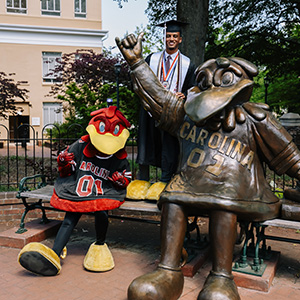 Cocky, Tra and the Cocky statue pose for a graduation picture