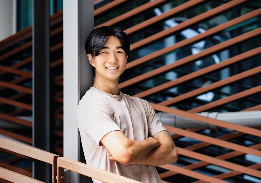 Jonathan Chen stands in front of the staircase at the Darla Moore School of Business.