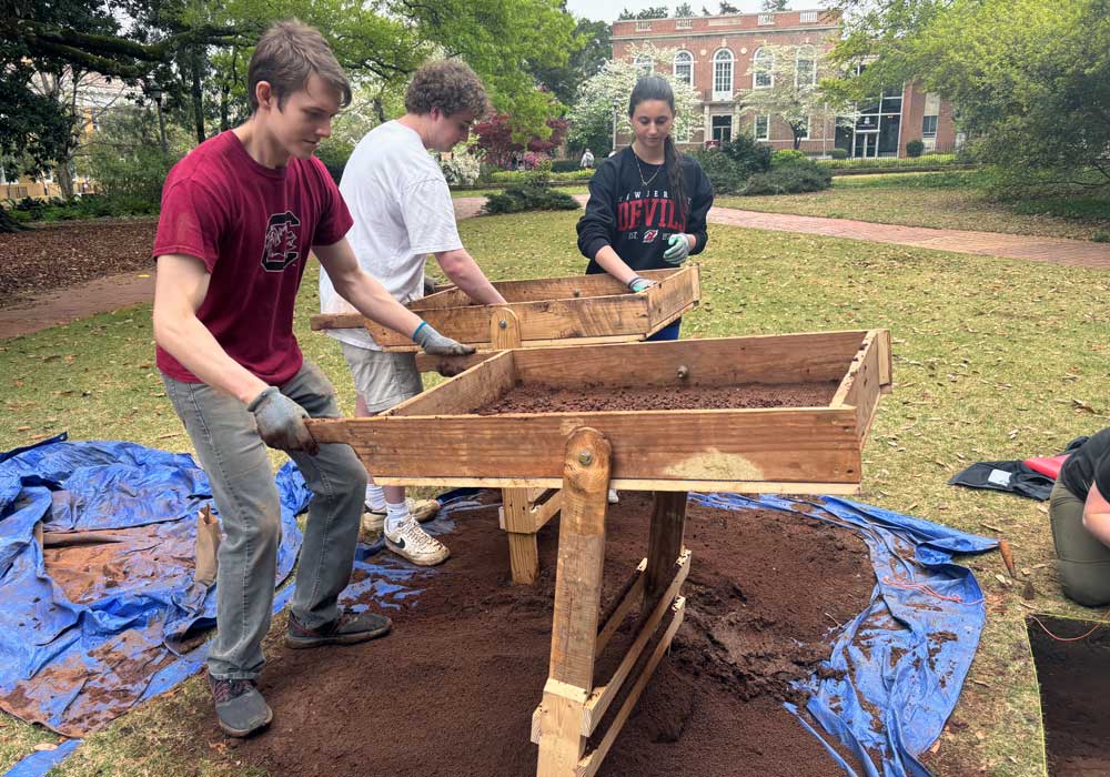 Eric Burkholder and other students shifts through dirt to look for archeological artifacts