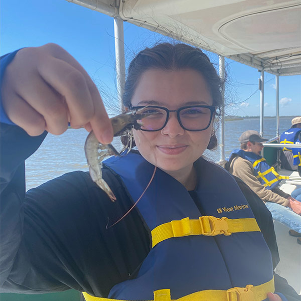 Alexis Yum holds a shrimp on a boat along the South Carolina coast.