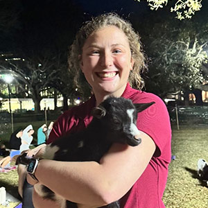 Caroline Sunderlage holds a small goat at goat yoga on campus.