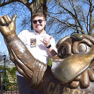 Greyson Carroway stands with the Cocky statue on campus.